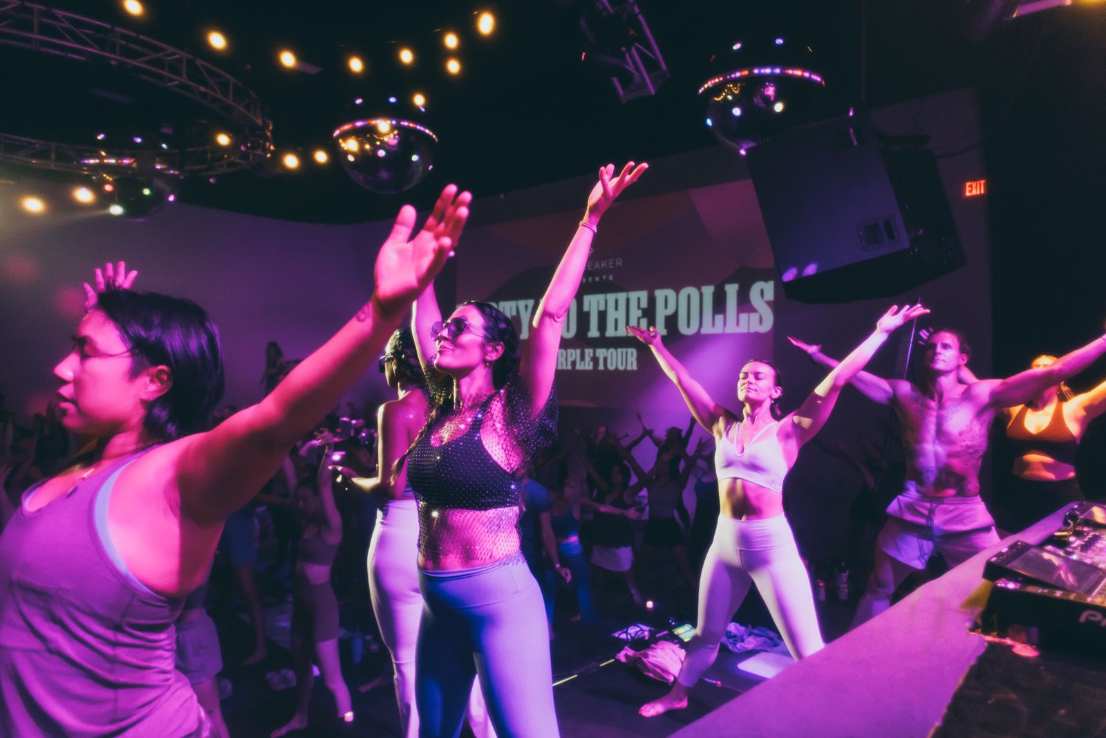 Dancers moving together under the Party to the Polls screen at a Daybreaker Purple Tour stop in Arizona